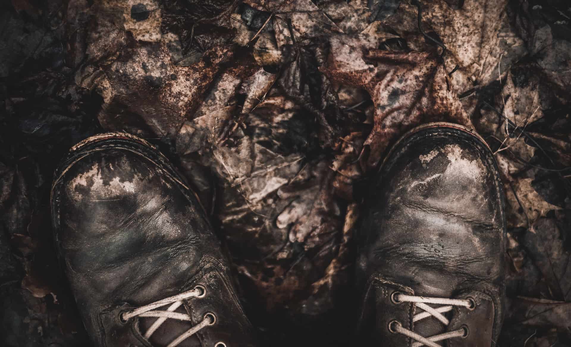 Worn hunting boots on wet leaves and trail dirt